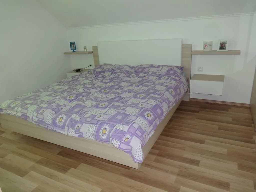 Spalnica s posteljo, vzglavjem s policami in nočnimi omaricami