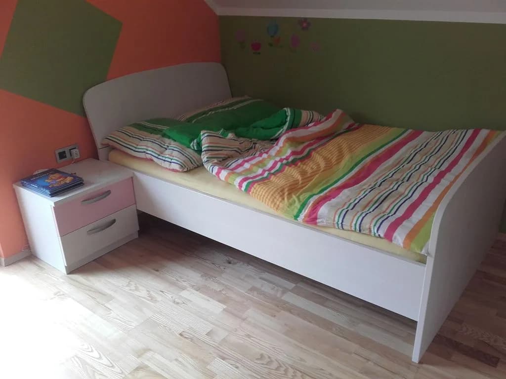 Otroška postelja z nočno omarico v barviti sobi