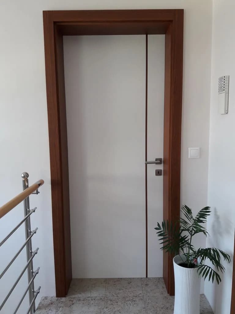 Bela vrata z orehovim podbojem ob stopnišču