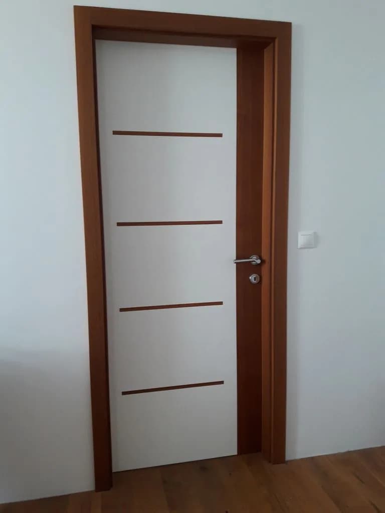 Bela vrata z lesenimi letvicami in orehovim podbojem