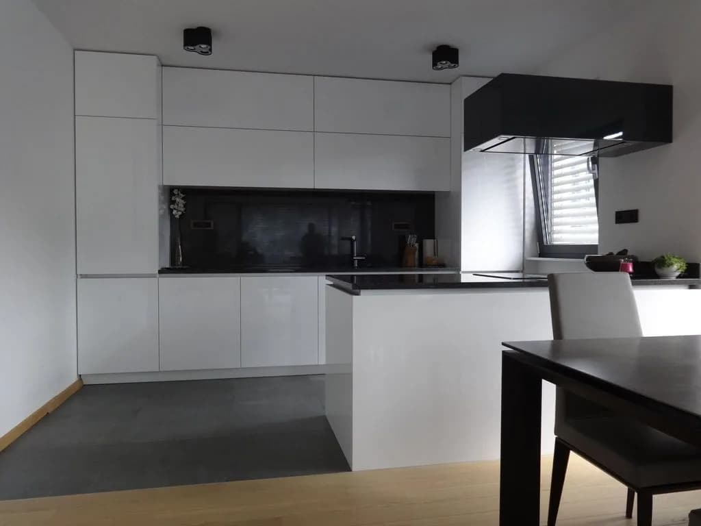 Minimalistična bela kuhinja s črnim zaledjem in otokom