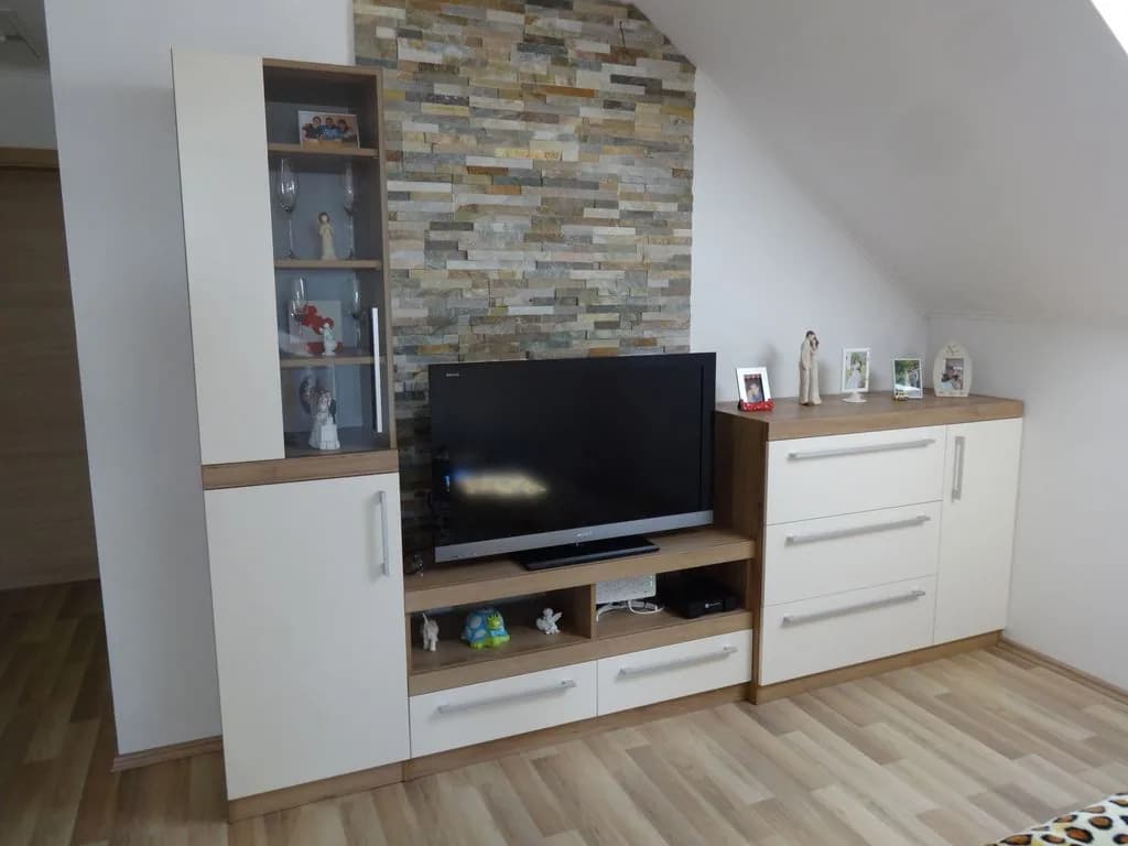Dnevna soba s TV-komodo in vitrino ob kamniti steni